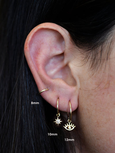 Anzie Mel Soldera evil eye charm set with diamonds suspended from a 14k yellow gold 8mm clicker hoop